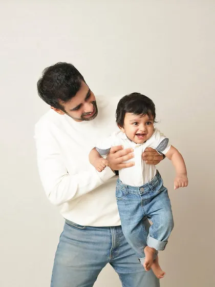 A candid shot of a father playing with his son. The movement and genuine laughter make this a dynamic and heartwarming family photograph.