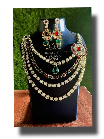 Make a statement at your next event with this multi-layered necklace. It combines rows of white stones with pops of red and green, making it a versatile piece that works for both weddings and parties.
