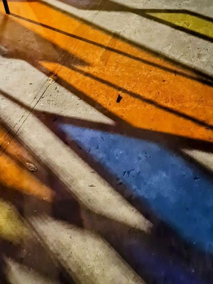 Colorful shadows cast by the 'Family Tree' installation on the pavement. Even the shadows become part of the artwork, creating an ever-changing pattern on the ground.