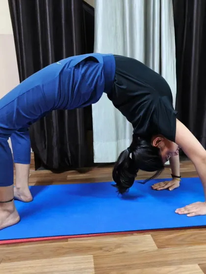 A student practices Chakrasana on her mat, demonstrating the strength and arch in her back. This asana stimulates the nervous system and leaves you feeling invigorated.