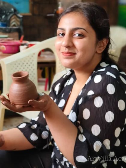 A participant smiles as she holds up the small vase she created. Even in a short workshop, you can learn the basics and make a piece to be proud of.