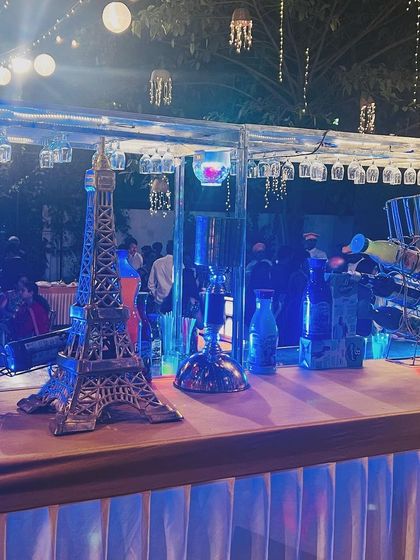 A stylishly decorated mocktail counter with blue lighting and Parisian-themed decor. I can customize the theme of my live counters to match your event's aesthetic.