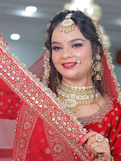 A playful shot of a bride holding her dupatta. Her makeup is glamorous, with a bright smile that lights up the photo.