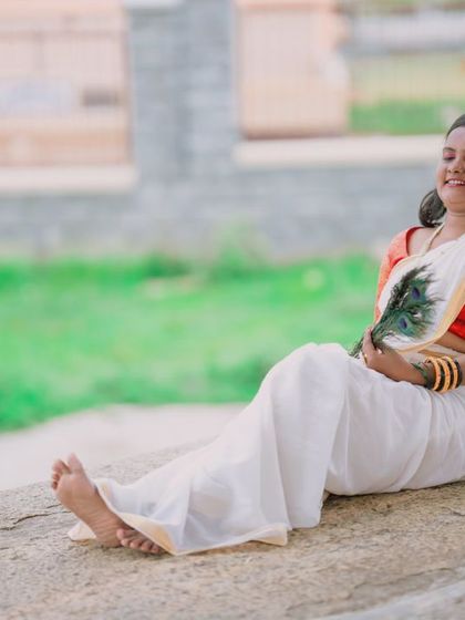 A lovely solo portrait of the woman in a traditional white and red saree, resting against a pillar. These individual shots are a beautiful part of any couple's session.