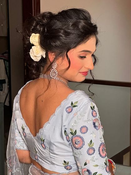 A beautiful, soft look for a party. The messy bun with white roses adds a romantic touch to her elegant floral saree.