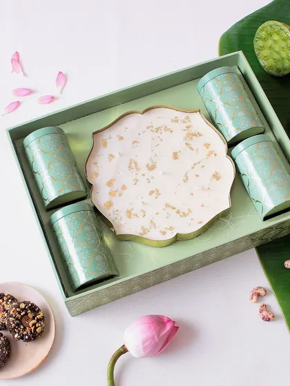 This luxe hamper is all about festivity and flavor. It comes with a big Urli candle and four tins filled with Sichuan peanut crunch, almond cookies, trail mix, and fruit & nut clusters.