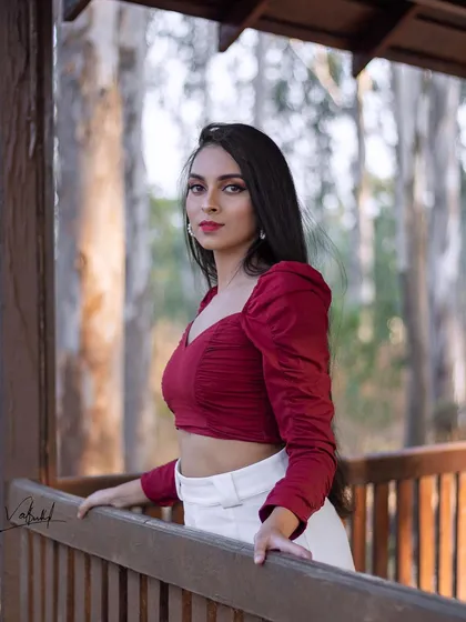 A beautiful portrait taken in a rustic wooden gazebo surrounded by nature. The model's confident gaze and the warm, natural lighting come together to create a simple yet stunning shot.
