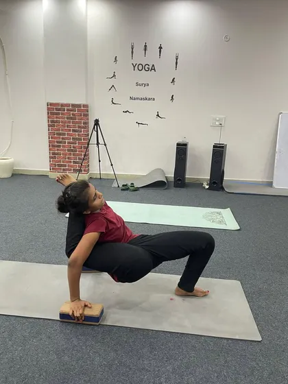 Using a block for support, this student practices an advanced one-handed arm balance, a pose that challenges stability and strength.