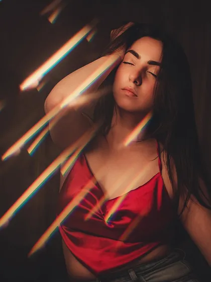 An artistic shot using a prism to create rainbow light flares, adding a creative touch to this portrait in a red top.