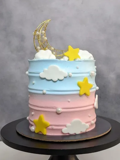 A tall and beautiful baby shower cake with a moon and stars theme, in soft pink and blue. Swipe to see the surprise.