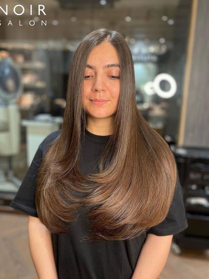 Beautiful, long hair with a soft chestnut hue. The layered cut and gentle coloring create a look that is both elegant and modern.