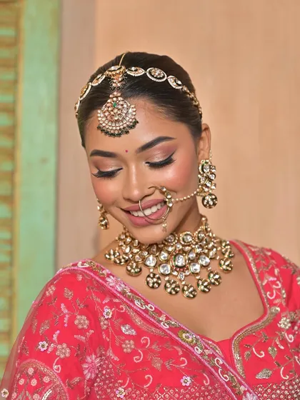 A close-up of a smiling bride, her face framed by her dupatta, showcasing her beautiful Kundan choker and nath.