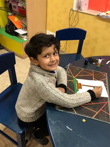 A smiling boy working on his Republic Day craft. We celebrate national holidays with special activities that foster a sense of patriotism.