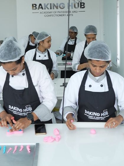 Teamwork in action. Students work together at a station, rolling and shaping fondant decorations. Our classes foster a sense of community and shared learning.