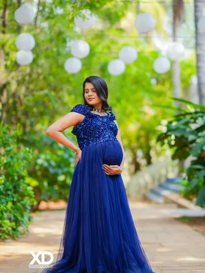 A beautiful solo portrait of the mother-to-be in a sparkling blue gown, cradling her baby bump in a garden.