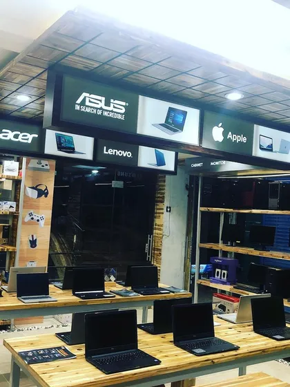 The multi-brand computer showroom uses a mix of wood textures on the ceiling and walls to create a warm, rustic-tech environment.