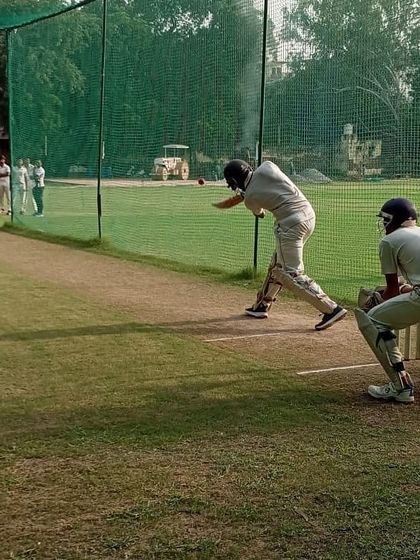 A batsman plays a powerful shot during net practice, with the wicketkeeper ready behind the stumps. This simulates match conditions to improve timing and shot selection.