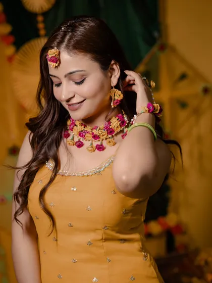 A candid moment of bride Nidhi admiring her floral jewelry during her Haldi photoshoot. These quiet, natural moments are just as beautiful as the posed ones.