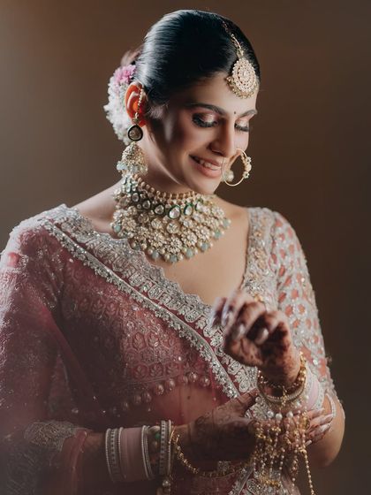 A graceful portrait of Vasudha adjusting her bangles. This shot captures a simple, elegant gesture, highlighting the beauty in the small, quiet moments of getting ready.