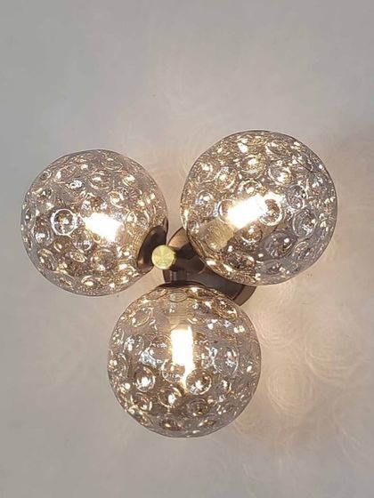 A wall or ceiling light with three textured globes, available in a warm amber or smoked grey finish.