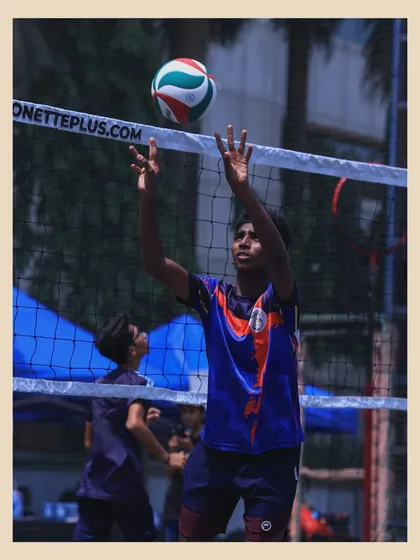 A player sets the ball with precision at the net. This image captures the focus and skill required to be a successful setter.
