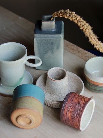 A sophisticated collection including a square vase, a cup and saucer set, and a wood grain textured tumbler, all from our Apr-May cohort.