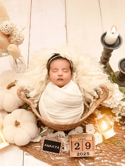 A beautiful, all-white rustic theme with a baby in a basket surrounded by white pumpkins, candles, and pampas grass. This setup is both modern and timeless.