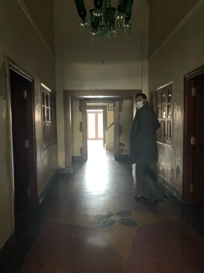 A glimpse down a corridor before restoration, showing the original patterned flooring and the play of light that we aim to enhance.