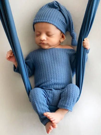 Gently suspended in a soft blue sling. This pose is not only beautiful but also keeps the baby feeling secure and comfortable, allowing for a deep sleep.