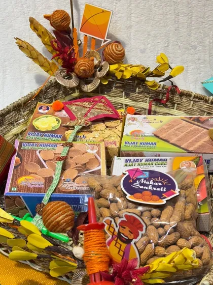 A rustic basket filled with Lohri essentials. This hamper includes peanuts, 'gajak', and other snacks, decorated with kite-themed elements for a festive touch.