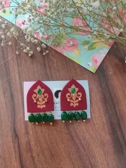 These hand-painted earrings are shaped like traditional arches and feature intricate designs with bead drops. They are available in both green and red, perfect for festive or wedding attire.
