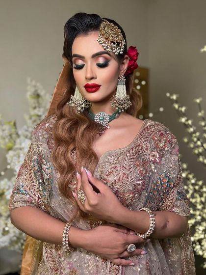 An advanced bridal makeup look for a stunning Nikkah ceremony. This look by Aanchal features dramatic eyes, bold red lips, and a glamorous side-parted hairstyle with a jhoomar.