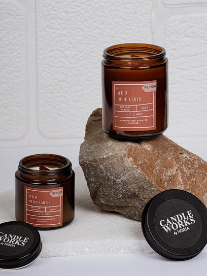 My "Wild Oudh Earth" candle has a deep, earthy, and sophisticated fragrance. Here you can see it in two sizes, both poured in amber jars that protect the fragrance oils and provide a warm, ambient glow.