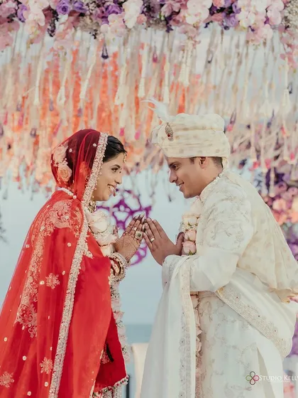 The couple shares a traditional greeting during their beachside wedding ceremony, a moment of mutual respect and love.