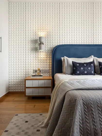 For this compact bedroom, we leaned into its cozy size to create a snug atmosphere. The highlight is the striking headboard wall, where a white checkered panel adds texture and visual interest, complemented by a rich blue fabric headboard for depth and sophistication.