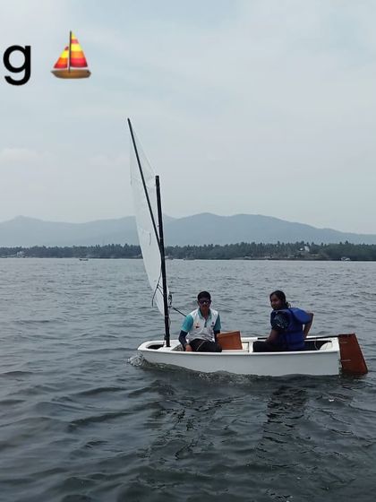 Two participants learn the basics of sailing, managing the sail and rudder on a small boat in Karwar.