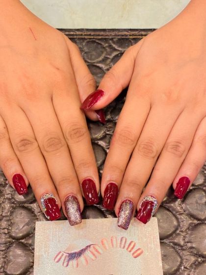 A sophisticated combination of deep red and silver on square nails. The design includes silver glitter accent nails and red nails with silver crystal details at the cuticle.