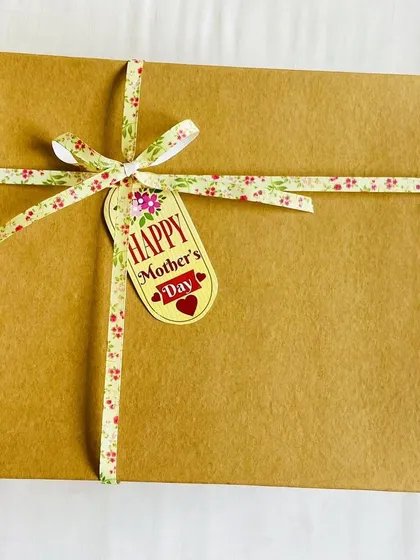 The simple, rustic packaging for our Mother's Day bakery box, tied with a floral ribbon and a 'Happy Mother's Day' tag.