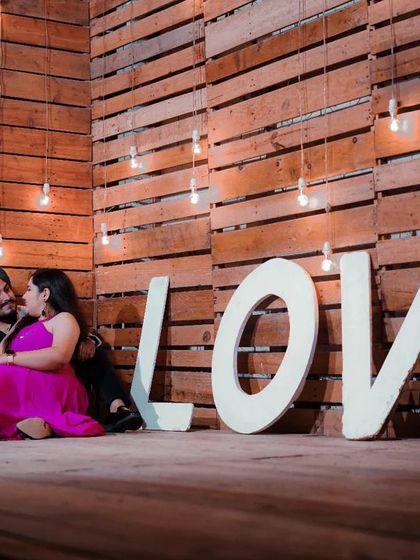 An intimate moment shared by a couple in front of our 'LOVE' sign and rustic wall. The inclusion of a guitar prop adds a personal and musical touch to their love story.