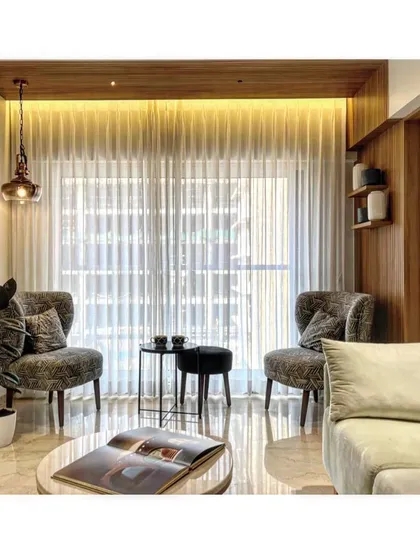 A cozy nook in the living room designed for conversation. The elegant armchairs, soft lighting, and sheer curtains create a perfect spot for a quiet chat or a cup of coffee.
