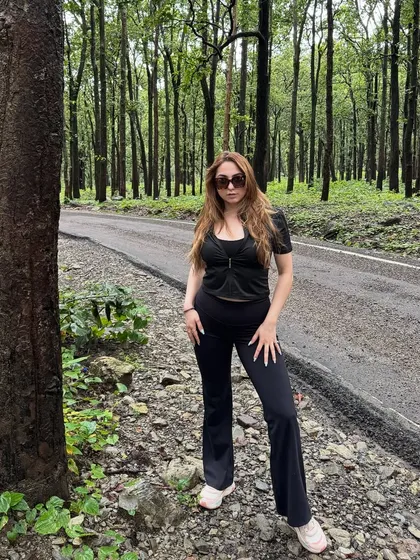 A full-length shot against the backdrop of tall trees in Jim Corbett, emphasizing the scale and beauty of the natural surroundings.