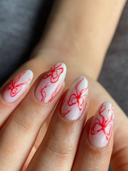 A delicate and trendy design featuring fine, hand-drawn red bows on a shimmery white base.