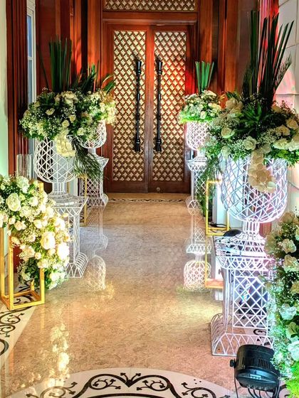 An elegant hallway arrangement, with large white floral displays in ornate wire-frame urns, creating a beautiful and sophisticated pathway.