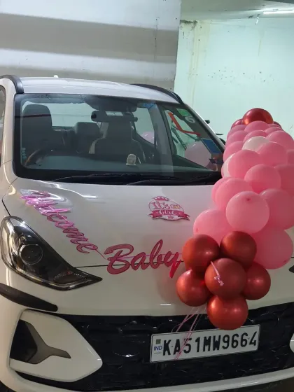 The fully decorated car ready to bring the baby princess home from the hospital. The pink balloon garlands on the hood and mirrors create a festive look.
