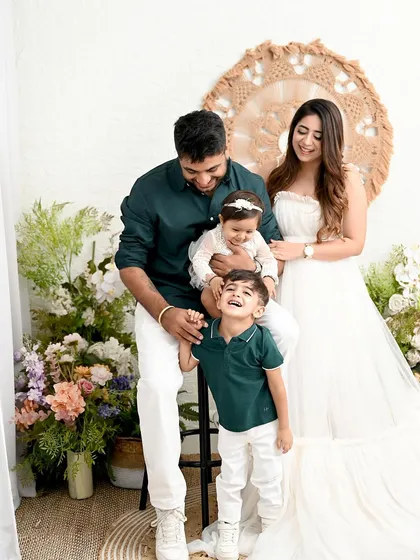 A picture-perfect family of four. The coordinated outfits in white and green, combined with a beautiful floral and boho setup, create a fresh, light, and airy family portrait.