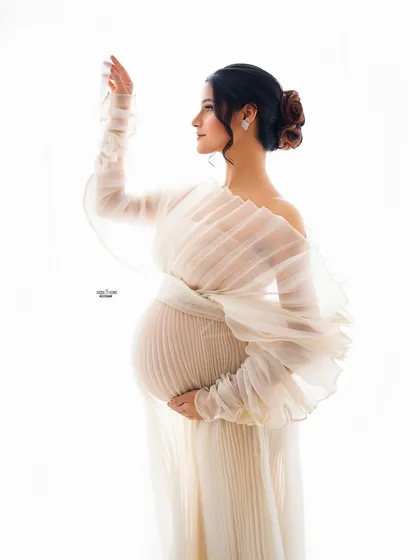 Ethereal, angelic, and absolutely glowing. This high-key studio portrait uses a delicate pleated white gown and bright lighting to create a soft, serene, and timeless look that beautifully showcases your pregnancy.