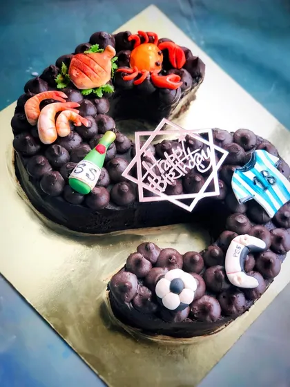 A personalized monogram cake in the shape of the letter 'S', covered in rich chocolate frosting and decorated with custom fondant toppers.