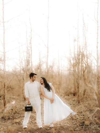 A playful and candid shot of the couple in the woods. Her fun pose and their shared smiles show the lighthearted and happy side of their relationship.