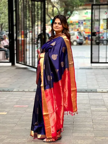 A client looking elegant in a deep blue and red silk saree. Her hair is styled with soft, voluminous waves.