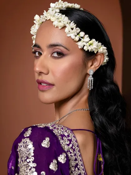 An editorial twist on a traditional mehendi look. We paired a vibrant purple outfit with a fresh jasmine floral headband. The makeup features a defined eye and a berry pink lip, creating a look that is both modern and rooted in tradition for a jewellery campaign.